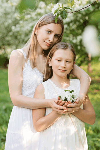 A mother and daughter are standing in the park