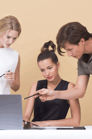 two women and a man looking on laptop